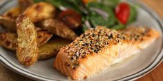 a plate with salmon, potatoes and salad on it