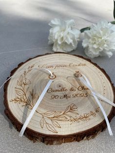 the wedding rings are placed on top of a tree slice with flowers in the background