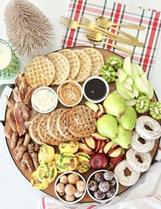 a platter filled with fruit, crackers and other food items next to a glass of milk