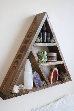 a wooden shelf filled with different types of essentials and herbs on top of a white wall