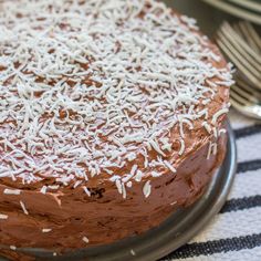 a chocolate cake with white frosting and sprinkles sitting on a plate