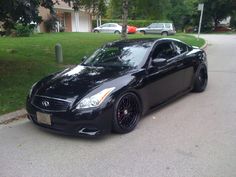 a black sports car parked on the side of the road in front of a house