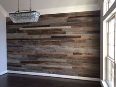 an empty room with wood paneling on the wall and chandelier hanging from the ceiling