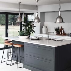 a kitchen island with stools in front of it and two lights hanging from the ceiling