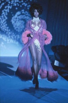 a model walks down the runway in a purple outfit with pink fur trimmings