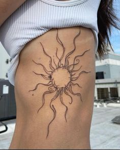 a woman's stomach with a sun tattoo on her lower back and the bottom part of her body