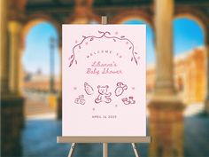 an easel with a baby shower sign on it in front of some arches and pillars