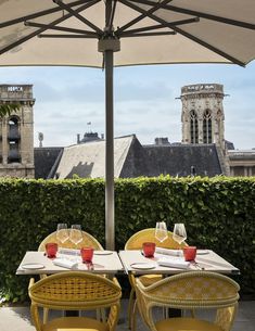 two yellow chairs sitting under an umbrella next to a table with plates and glasses on it