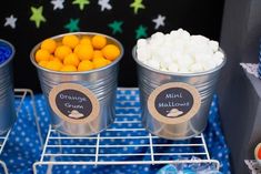 three buckets filled with marshmallows sitting on top of a blue table cloth