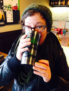 a woman drinking from a stainless steel coffee mug