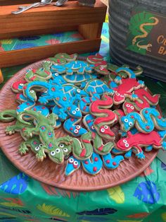 decorated cookies sitting on top of a pink plate next to a green and blue table cloth