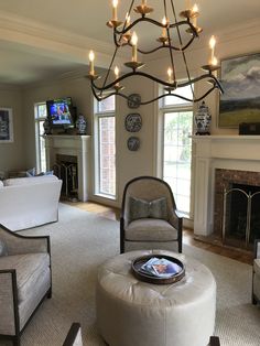 a living room filled with furniture and a chandelier hanging over the fire place