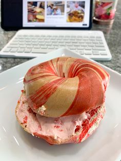 a plate with a doughnut covered in icing next to a laptop on a table