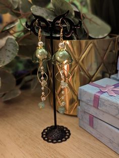 These handmade olive green jellyfish earrings with pearls and crystals are perfect gifts for anyone who loves the ocean. Delicate light green glass sits among white pearls with small jade crystals dangling from hand-twisted wire swirls. You can select either small or large jellyfish sizes paired with gold or silver embellishments. Average total length of each earring is 4 inches. Bead Cap Drop Earrings For Gift, Bead Cap Drop Earrings As Gift, Bead Caps Drop Earrings As Gift, Adjustable Beaded Pearl Earrings As Gift, Green Dangle Jewelry With Bead Caps, Green Pearl Drop Earrings For Gift, Green Pearl Drop Earrings As Gift, Handmade Green Pearl Earrings For Gift, Handmade Adjustable Pearl Earrings For Party