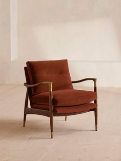 a red chair sitting on top of a hard wood floor next to a white wall