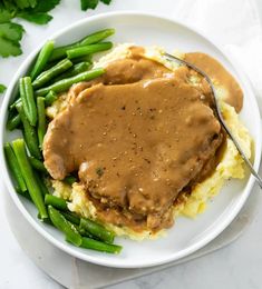 a plate with mashed potatoes, green beans and gravy