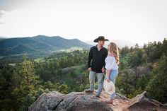 a man and woman standing on top of a mountain