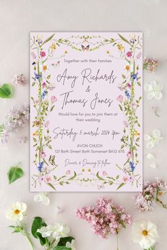 the wedding card is surrounded by flowers and greenery