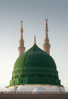 a large green dome on top of a building with two minalis in the background