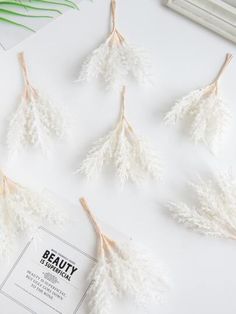 four white flowers are hanging from the side of a book on top of a table