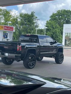 a black truck parked in front of a gas station