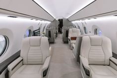 the inside of an airplane with white leather seats and two rows of windows on each side