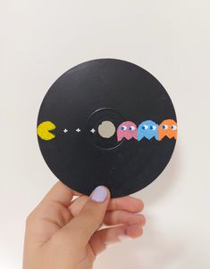 a hand holding a black record with pacman stickers on it