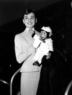 an old photo of a woman holding a small doll in her arms and smiling at the camera