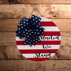 a patriotic sign with the words united we stand hanging on a wooden wall next to a pair of scissors