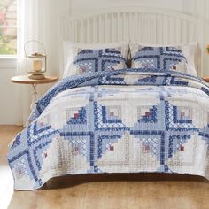 a blue and white quilted bedspread on a bed with two night stands