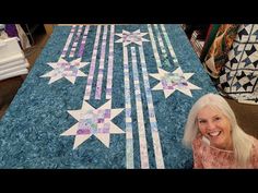 a woman sitting in front of a quilted table top with white stars on it