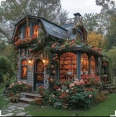 a small house with lots of flowers growing on the front and side of it's windows