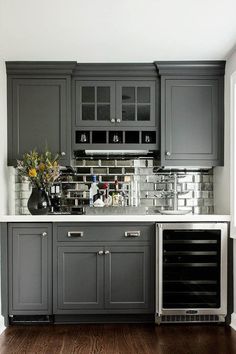 a kitchen with gray cabinets and white counter tops, an oven and wine cooler in the corner