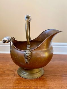 a metal bowl with an animal head in it on top of a hard wood floor