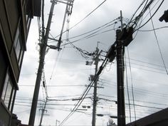 power lines and telephone poles on a cloudy day in an urban area, with the sky above them