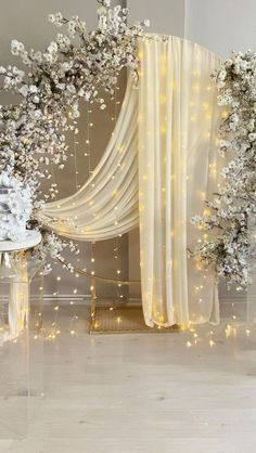 a white wedding cake sitting on top of a table next to a flower covered wall