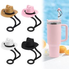 four different colored hats are next to a cup with a straw and an orange slice