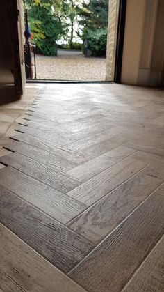 an open door leading into a house with wood flooring on the outside and inside