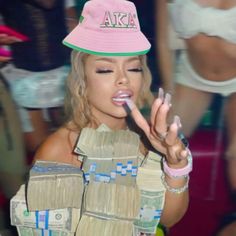 a woman wearing a pink hat and making a hand gesture with money in front of her