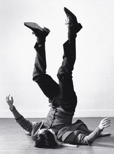 a man laying on the floor with his feet up in the air while wearing a hat