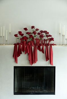 a fireplace with red bows and candles on the mantel above it is decorated with flowers