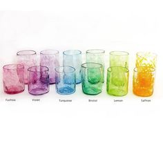 a group of colorful glasses sitting next to each other on a white surface with no one around them