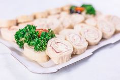 an assortment of food items displayed on a white platter, including meats and veggies