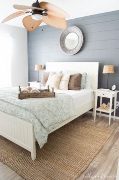 a bedroom with a white bed and wooden ceiling fan in the middle of the room