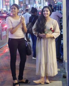 two women standing next to each other on a sidewalk