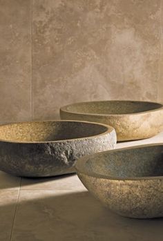 three large stone bowls sitting on top of a tiled floor in front of a wall