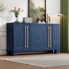 a blue sideboard with gold handles in a living room next to a painting on the wall