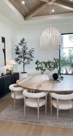 a dining room table with white chairs and a chandelier hanging from the ceiling