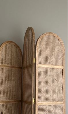 an open wooden screen with wicker panels on the top and bottom panel, in front of a gray wall