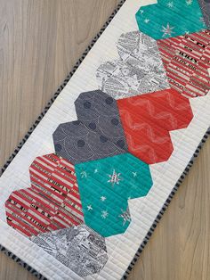 a close up of a quilted table runner on a wooden floor with wood floors